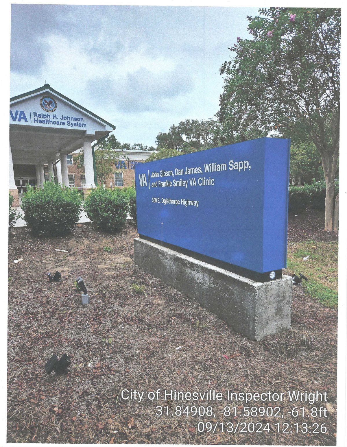 The Hinesville VA clinic: the building portico reads 'Ralph H. Johnson Healthcare System' while a smaller monument sign reads 'John Gibson, Dan James, William Sapp, and Frankie Smiley VA Clinic.'
